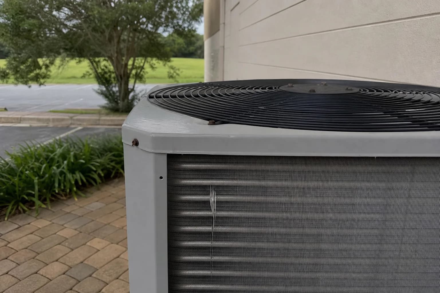 AC condenser being serviced at a Foley inland Baldwin County home, standing-distance view, summer
