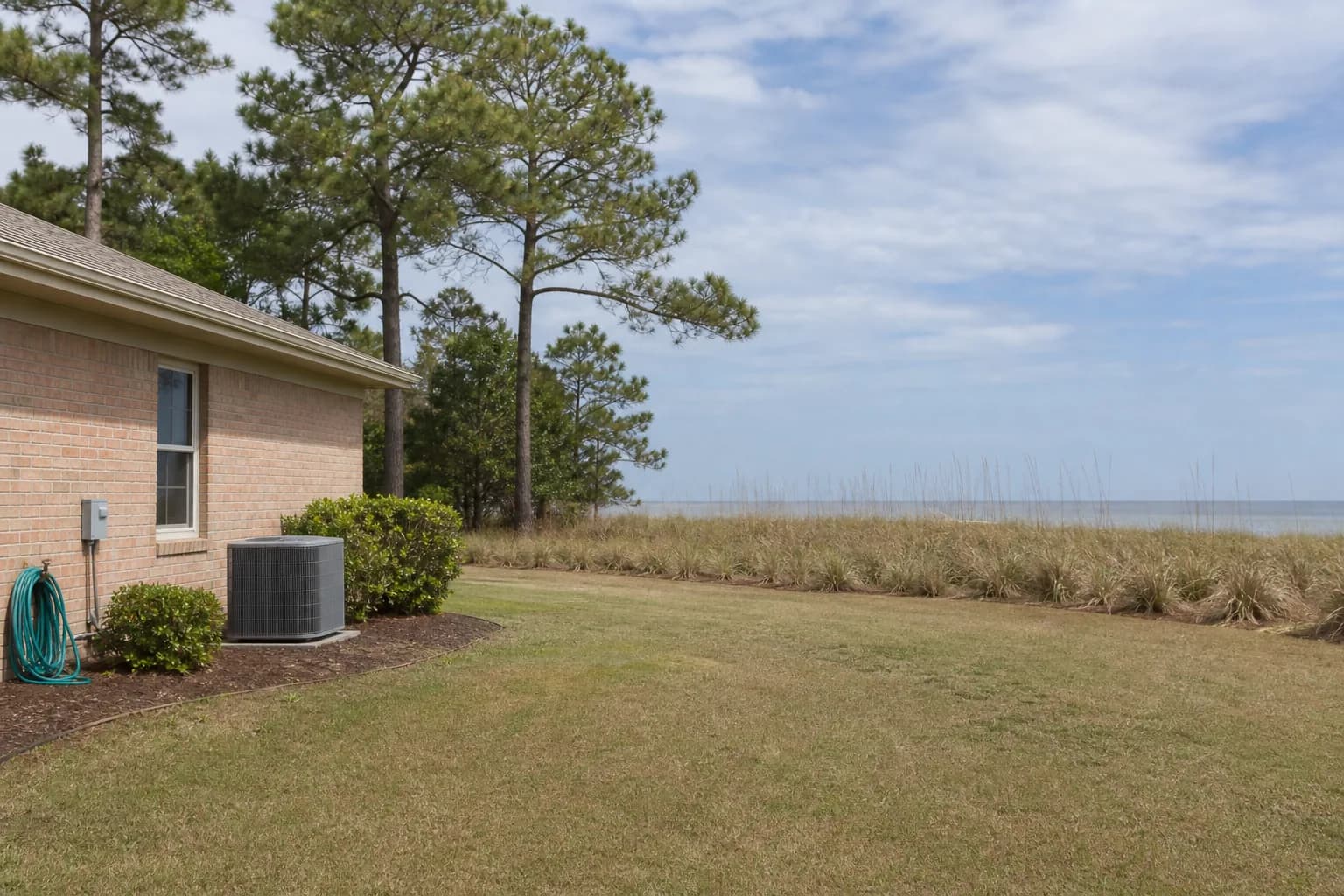 AC unit being maintained at an Orange Beach Gulf-front home, backyard view, spring