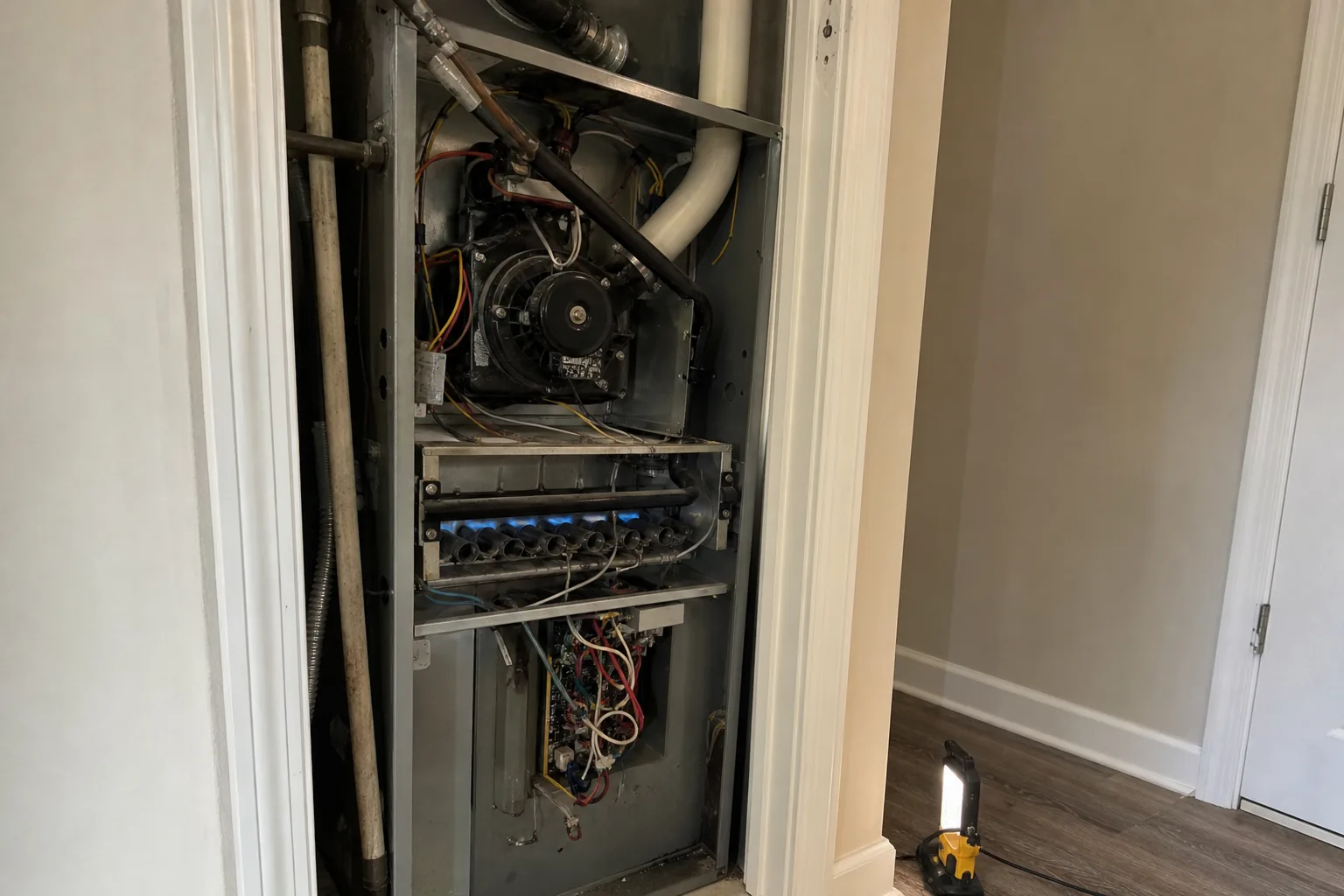 Gas furnace being serviced in a Gulf Shores home hallway, indoor detail