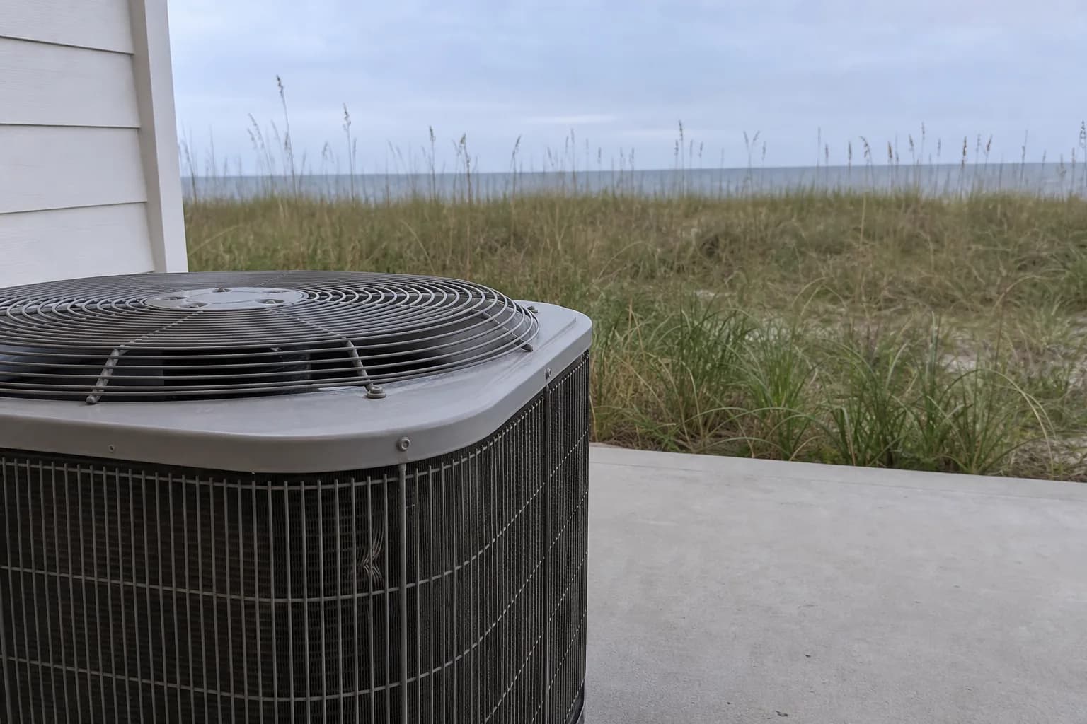 AC condenser being serviced at an Orange Beach Gulf-front home, pad view, summer
