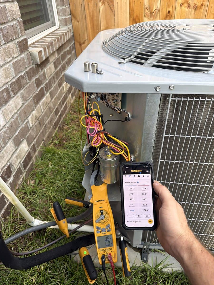 Clamp meter and phone showing live refrigerant and air-side readings at an outdoor condensing unit