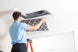 Homeowner replacing a dirty air filter at a ceiling return vent